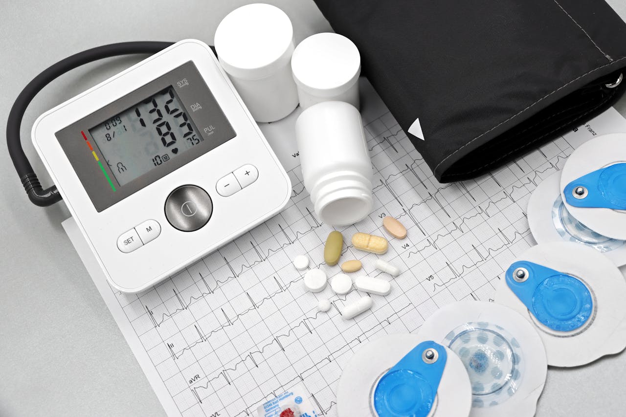 gallery-4 Flat lay of blood pressure monitor, pills, and ECG printout for heart health theme.