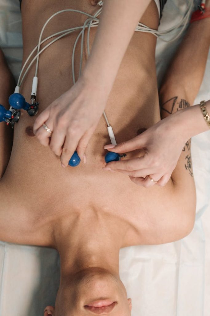 pexels photo 7108341 Close-up of a healthcare professional placing ECG electrodes on a patient's chest for heart monitoring.