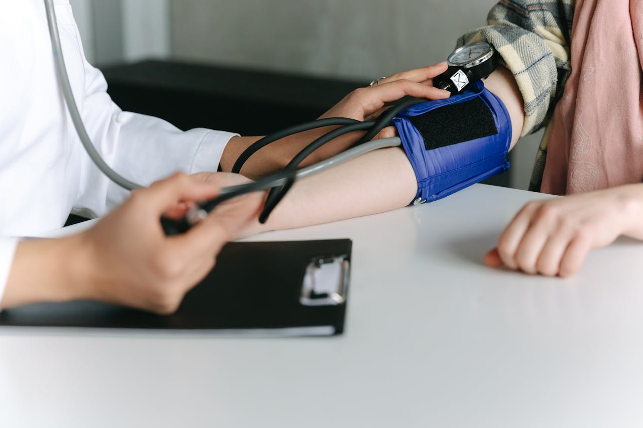 ours-journey A healthcare worker uses a sphygmomanometer to check a patient's blood pressure in a medical office.