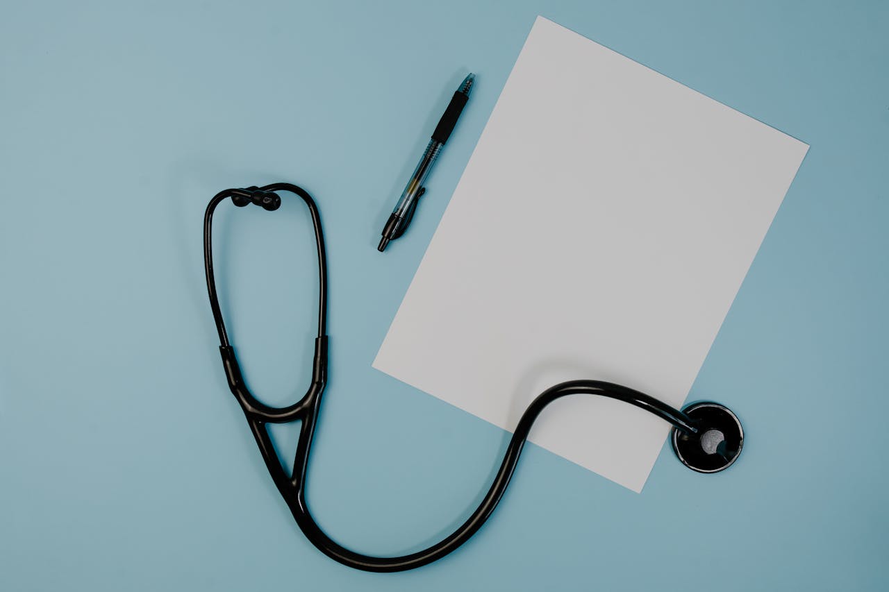 our-services-3 Flat lay of stethoscope, blank paper, and pen on blue surface, ideal for medical themes.